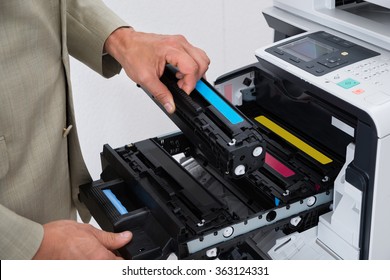 Cropped image of businessman fixing cartridge in photocopy machine at office