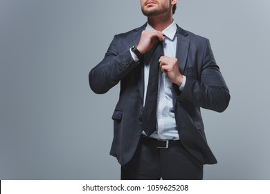 cropped image of businessman fixing tie isolated on grey