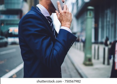 Cropped image of businessman holding phone in hands while having phone conversation during walk to office, close up male person in suit calling mobile in roaming using tariffs, people communicating  - Powered by Shutterstock