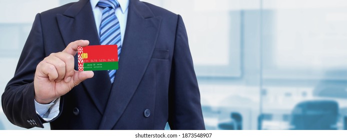 Cropped image of businessman holding plastic credit card with printed flag of Belarus. Background blurred.