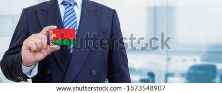 Cropped image of businessman holding plastic credit card with printed flag of Belarus. Background blurred.