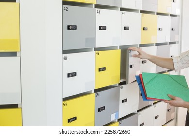 Cropped image of businessman putting files in locker at creative office - Powered by Shutterstock