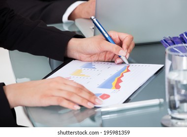 Cropped image of businesswoman writing on graph at desk in office