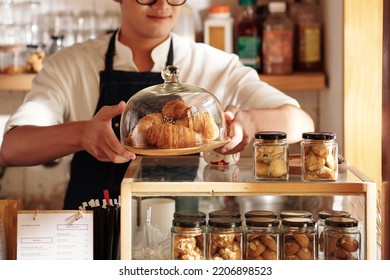 Cropped image of cafe waiter putting plate with fresh croissants on counter to sell - Powered by Shutterstock