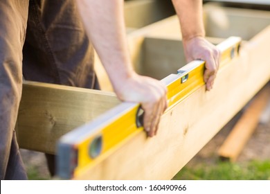 Cropped image of carpenter's hands checking level of wood at construction site