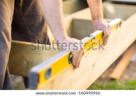 Cropped image of carpenter's hands checking level of wood at construction site