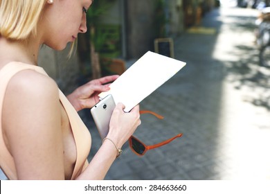 Cropped Image Caucasian Female Tourist Holding Blank Copy Space Paper And Smart Phone In The Hands While She Strolling In The City,young Gorgeous Woman Read Empty Flyer While Standing In Urban Setting