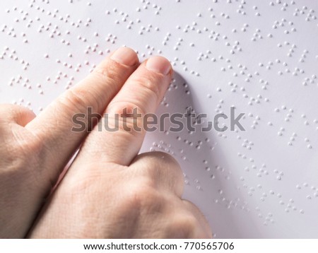Cropped image of child using braille to read book at school