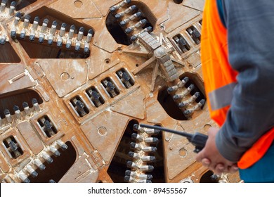Cropped image of construction worker in front of tunnel boring machine, focus on machine