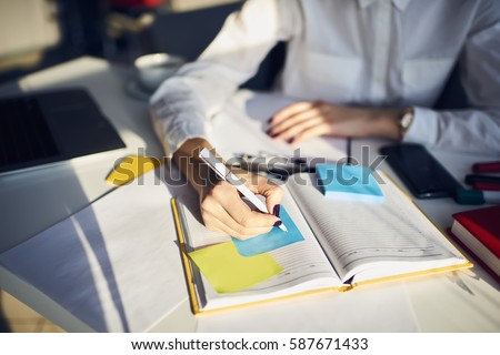 Cropped image of creative female secretary creating planning for executive noting important meeting and events organizing work of busy boss while sitting at working place in coworking office