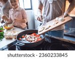 Cropped image of cute little girl and her beautiful parents cooking together in kitchen at home