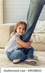 Cropped Image Of Cute Little Girl Looking At Camera And Smiling While Hugging Her Father's Leg Not Letting Him Go