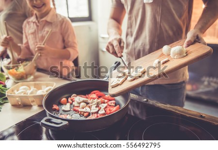 Cropped image of cute little girl and her beautiful parents cooking together in kitchen at home