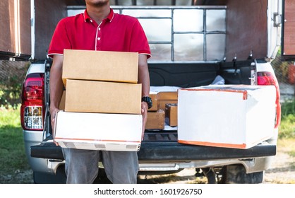 Cropped Image Of Delivery Man Standing And Holding Many Parcel Boxes At His Pickup.