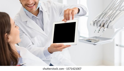 Cropped image of dentist showing patient blank digital tablet screen, dental clinic, panorama - Powered by Shutterstock