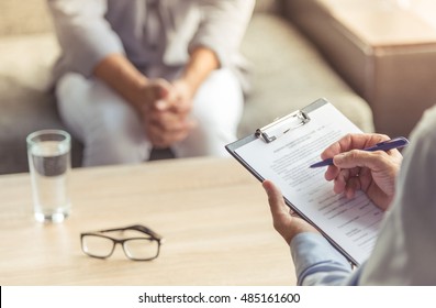 Cropped image of depressed man at the psychotherapist. Doctor is making notes while listening to his patient - Shutterstock ID 485161600