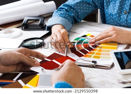 Cropped image of designer and client meeting in office. Creative workspace with color swatches and tablet computer. Interior and textile designing. Coloristics and product branding in design studio.