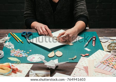 cropped image of designer cutting paper for scrapbooking greeting postcards