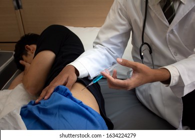 Cropped Image Of Doctor With Patient Getting Ready For Buttocks Injection Syringe Shot At A Hospital