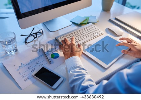 Cropped image of entrepreneur using computer and digital tablet in his work