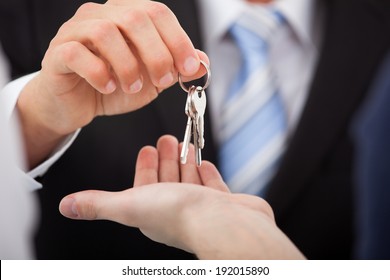 Cropped image of estate agent giving house keys to man in office