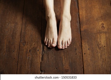 Cropped Image Of Female Bare Feet On A Wooden Floor