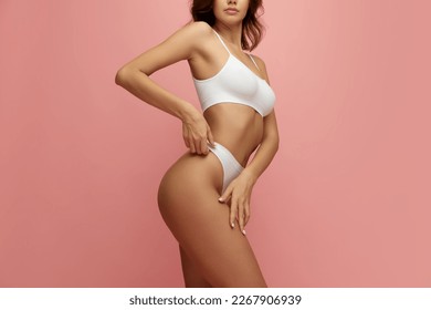 Cropped image of female body, breast in white underwear isolated over pink studio background. Mammoplasty. Concept of beauty, body and skin care, health, plastic surgery, cosmetics