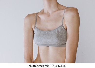 Cropped Image Of Female Breast In Cotton Underwear Isolated Over Grey Studio Background. Plastic Surgery. Mammoplasty. Concept Of Beauty, Body And Skin Care, Health, Spa, Cosmetics, Wellness, Ad