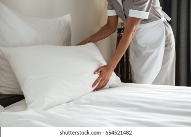 Cropped image of a female chambermaid making bed in hotel room - Shutterstock ID 654521482