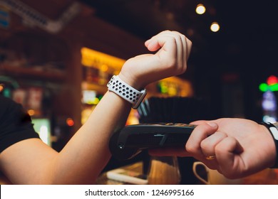 Cropped image of female customer paying through smart watch at bar. - Powered by Shutterstock