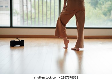 Cropped Image Of Female Dancer In Wide Pants Standing At Big Studio Window, View From Behind