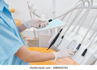 Cropped image of female dentist in rubber gloves checking handpieces used in dentistry