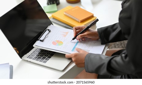 Cropped Image Of Female Executive Checking Financial Statement On The Data Chart Report At Her Desk.