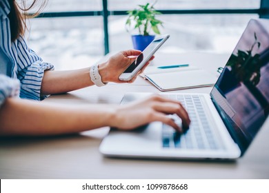 Cropped image of female holding smartphone getting message with confirmation making transaction on laptop computer,woman using mobile phone app for synchronizing data with netbook via bluetooth