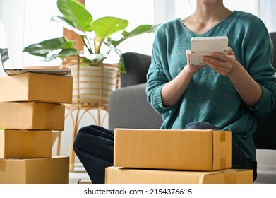 Cropped Image, Female Online Seller Using Calculator To Calculate The Delivery Fee For Her Packages.