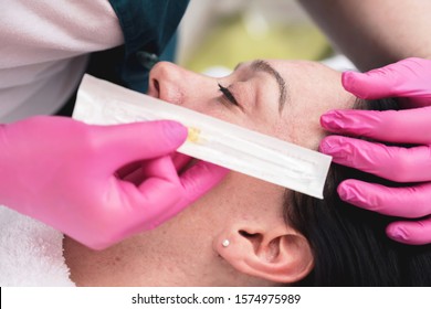 Cropped Image Of Female Patient Lying Down In Cosmetic Beauty Salon. Closeup Of Syringe Near Her Face With Doctor Gloves. Cosmetology Concept.