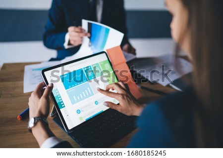 Cropped image of female professional checking financial website with revenue statistics and marketing infographics, expert woman browsing web page with graph charts of corporate monetary gain