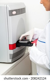 Cropped image of female researcher placing samples in machine at lab