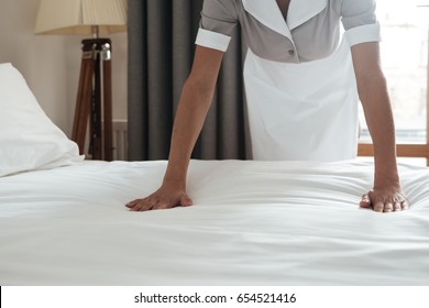 Cropped image of a female young maid making bed in hotel room - Shutterstock ID 654521416