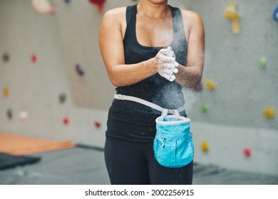 Cropped image of fit woman coating hands in powder chalk magnesium before starting to train in indoor climbing center - Powered by Shutterstock