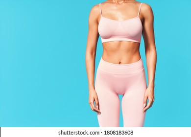 Cropped image of fit woman torso on blue background with copy space. Female with perfect abdomen muscles