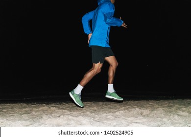 Cropped Image Of A Fit Young African Sports Man Wearing Windbreaker Exercising Outdoors At Night Time, Running At The Beach