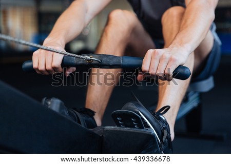Cropped image of a fitness man using rowing machine in the gym