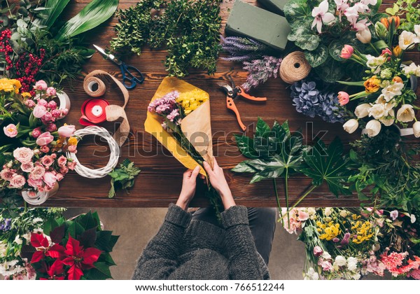 cropped image of florist wrapping bouquet in pack\
paper in shop