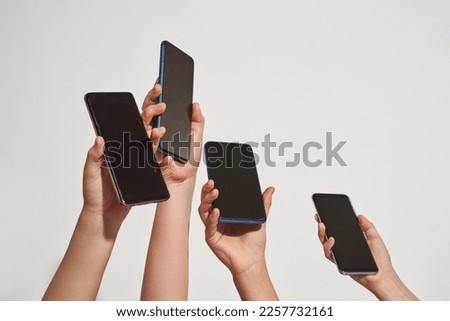 Cropped image of four children of zoomer generation hands holding smartphones. Gadget addiction. Concept of modern youngster lifestyle. Isolated on white background. Studio shoot. Copy space