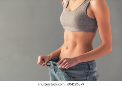 Cropped image of girl pulling her big jeans and showing weight loss - Shutterstock ID 604196579
