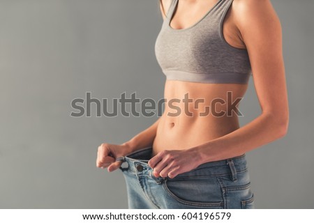 Cropped image of girl pulling her big jeans and showing weight loss