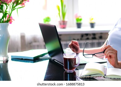 Cropped Image Of A Girl Or Woman Working On Quarantine From Home On The Kitchen Wearing Pijama.Home Office Or Distance Learning Concept. Freelance Or E-learning.Coffee Break.