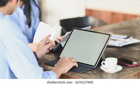 Cropped image of graphic designer team working together with computer tablet and document/information at the wooden meeting table over vintage office as background. - Powered by Shutterstock