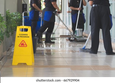 Cropped image of group of woman in protective gloves using a flat wet-mop and machine while cleaning floor - Shutterstock ID 667929904